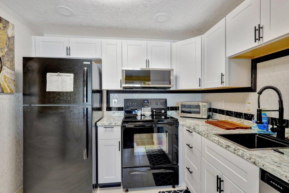 278 Monaco Way, Unit F Delray Beach, FL 33446 - Photo 3 of 19 a kitchen with stainless steel appliances granite countertop a refrigerator a stove a sink and a microwave