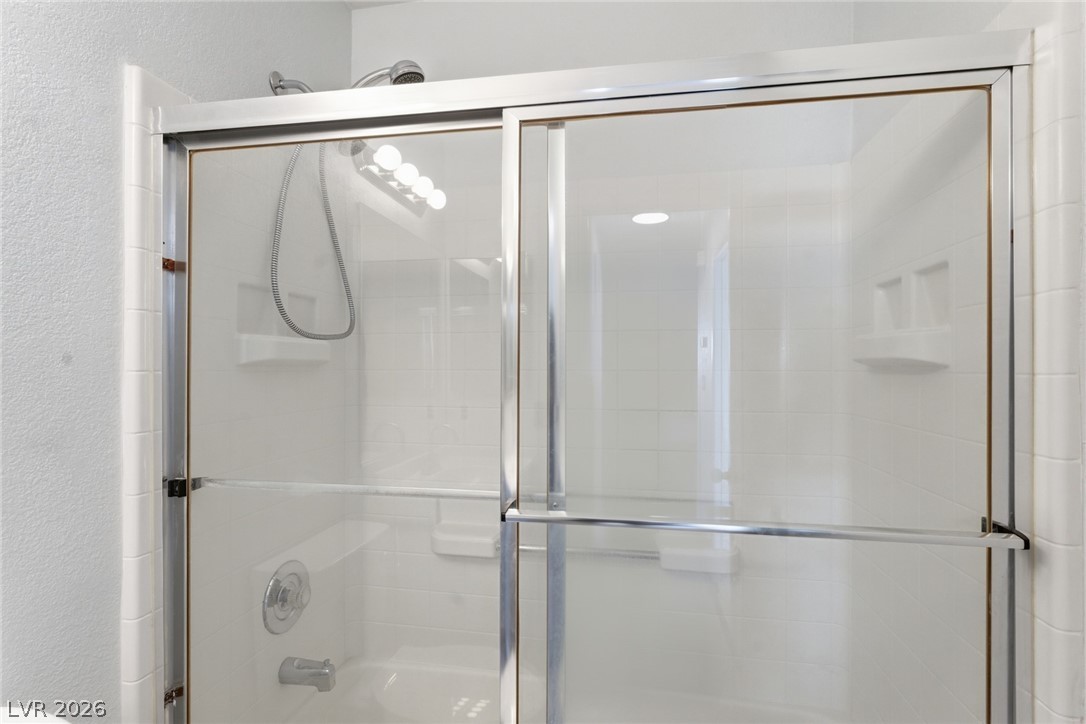 5449 Bugle Way, Unit 104 Las Vegas, NV 89108 - Photo 19 of 33 This bright bathroom features a functional tub and shower combination with sliding glass doors.