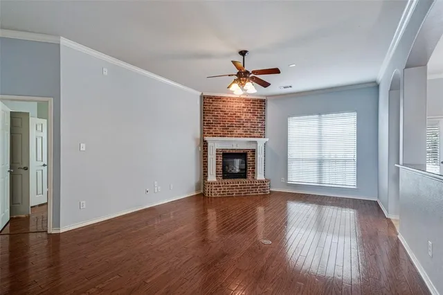 a view of an empty room with wooden floor fireplace and a window