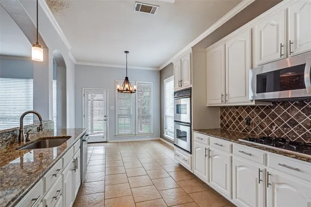 a kitchen with granite countertop a stove a sink a refrigerator and cabinets