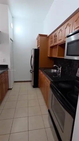 a kitchen with granite countertop a refrigerator and a stove top oven