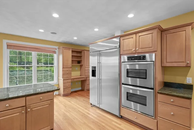 a kitchen with granite countertop stainless steel appliances a refrigerator cabinets and wooden floor