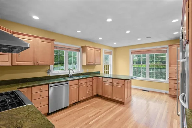 a large kitchen with stainless steel appliances granite countertop a sink and wooden cabinets