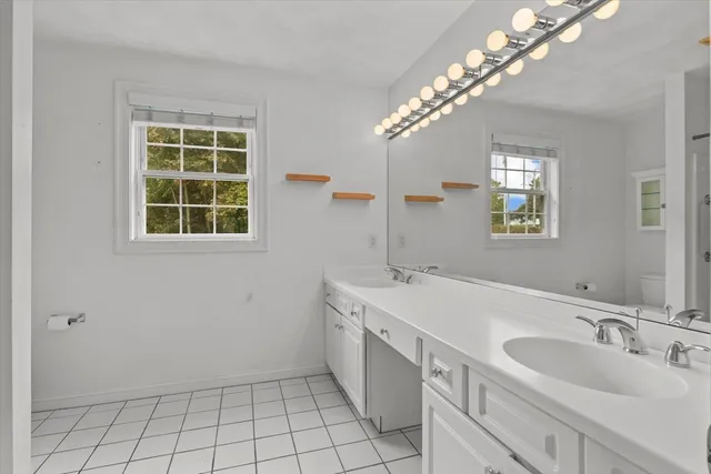 a spacious bathroom with a double vanity sink a large mirror and a shower