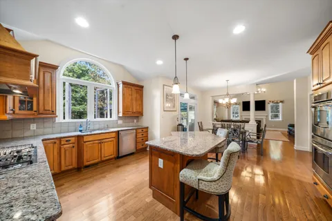 a large kitchen with granite countertop lots of counter space dining table and stainless steel appliances