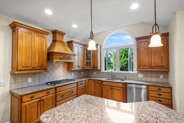 a kitchen with stainless steel appliances granite countertop a sink a stove and a wooden cabinets