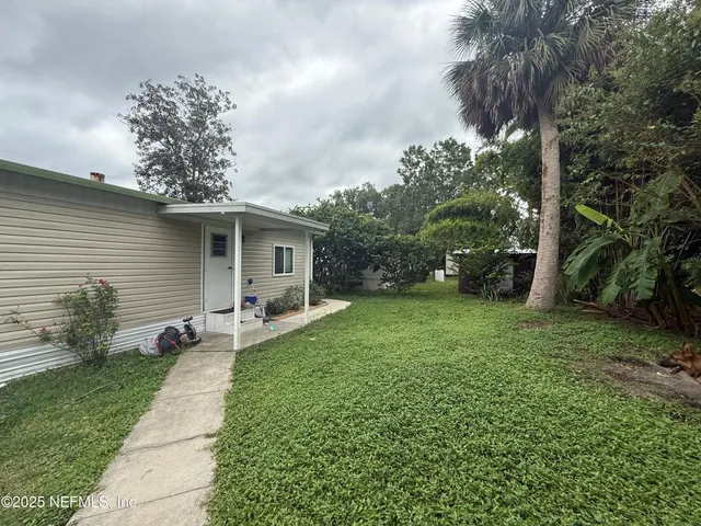 a backyard of a house with table and chairs plants and large tree