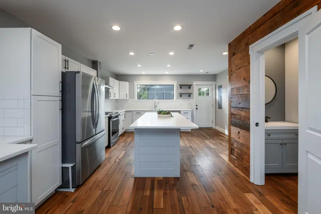 a large kitchen with stainless steel appliances refrigerator a stove and wooden floor