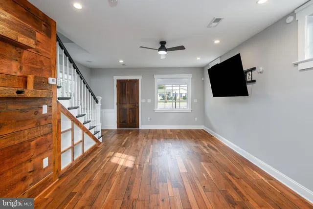 a view of empty room with wooden floor and fan