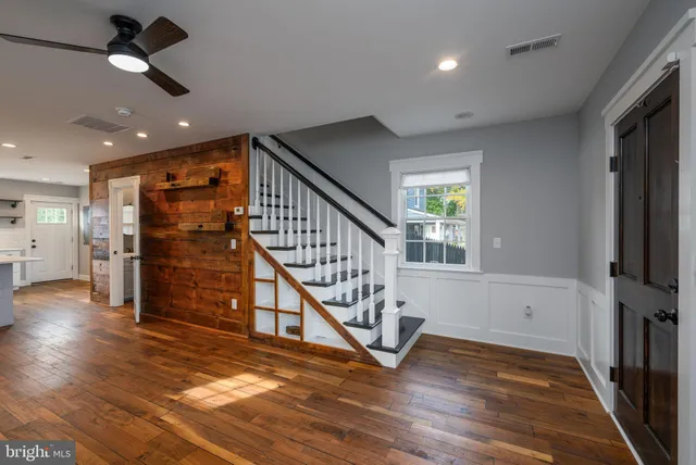 an empty room with wooden floor stairs and windows