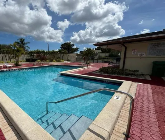 a view of a swimming pool with lawn chairs and a fire pit