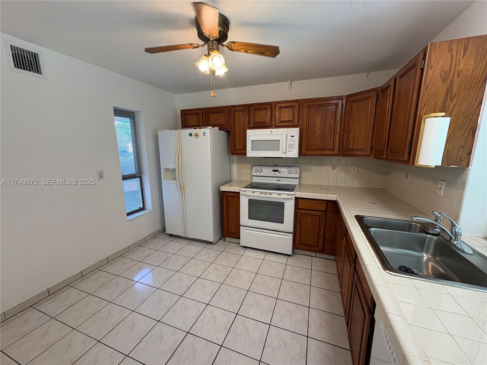 11260 Southwest 172nd Street, Unit II2831 Miami, FL 33157 - Photo 5 of 24 a kitchen with a stove a refrigerator and a sink
