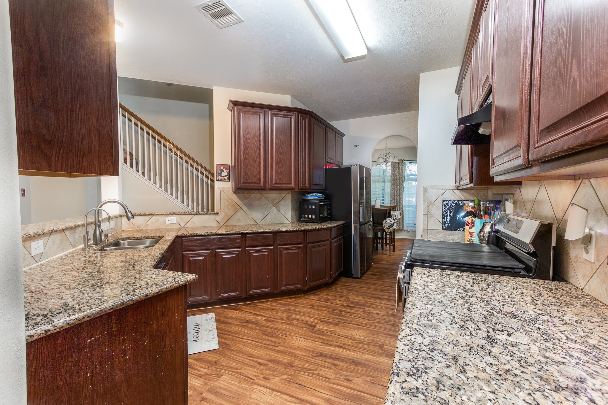 1107 Arum Road Missouri City, TX 77489 - Photo 3 of 23 Beautiful kitchen with an abundance of cabinet & counter space is a chef's delight. Beautiful granite counter tops and recent laminate flooring, this kitchen features stainless steel freestanding gas stove/oven and dishwasher.