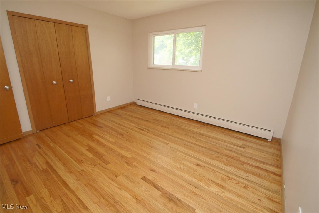 7958 Bellflower Road Mentor, OH 44060 - Photo 26 of 34 Unfurnished bedroom featuring baseboard heating, light wood-style flooring, and a closet