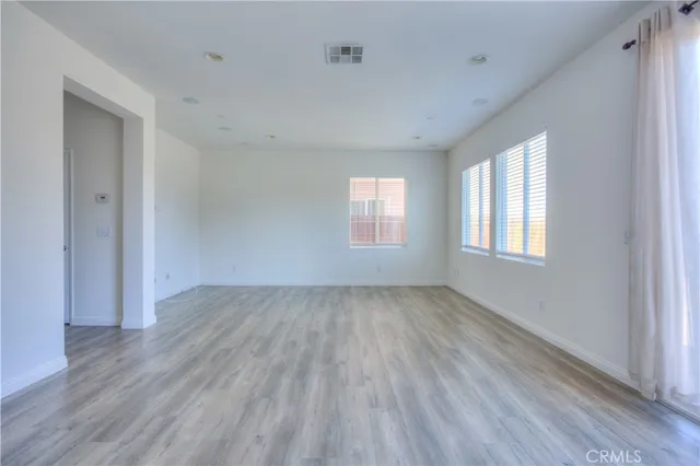 a view of an empty room with wooden floor and window