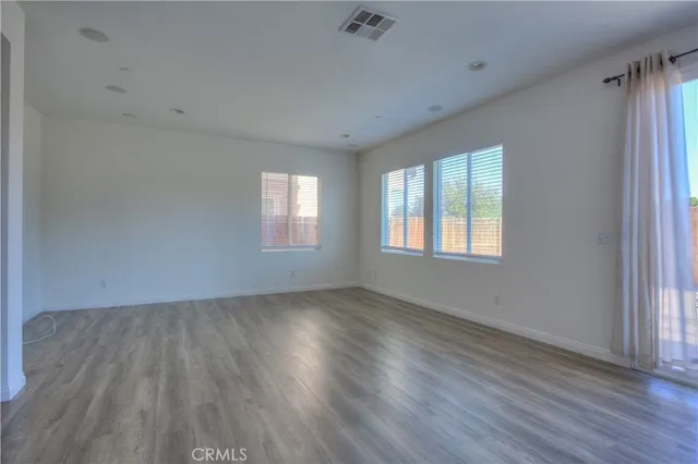 a view of an empty room with wooden floor and window