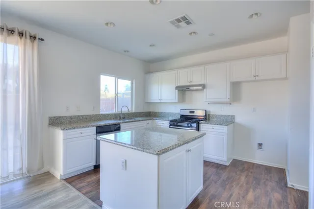 a kitchen with granite countertop a sink stove and cabinets