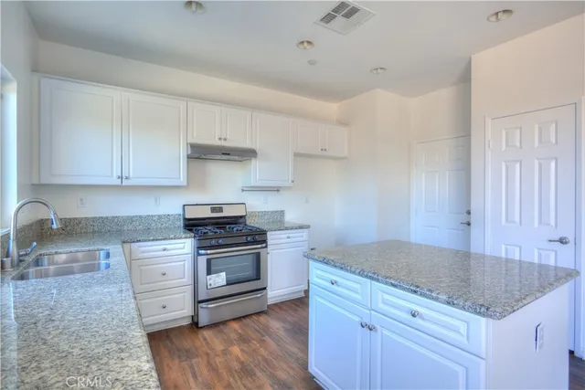 a kitchen with granite countertop a sink and a stove top oven