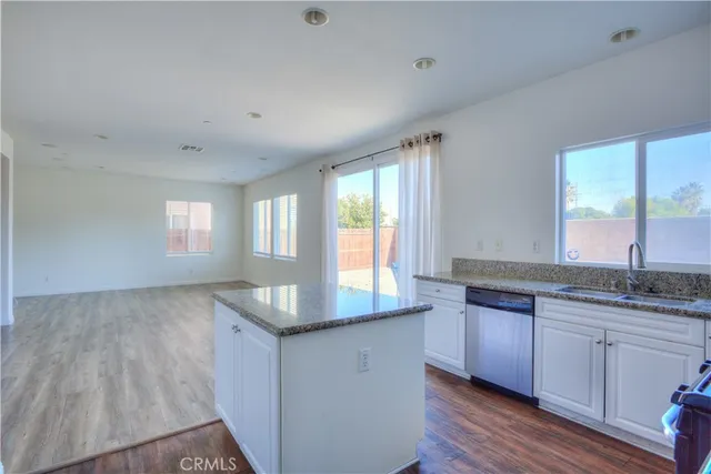 a kitchen with granite countertop a sink window and cabinets