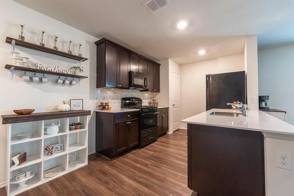 a kitchen with stainless steel appliances a sink dishwasher stove refrigerator and cabinets with wooden floor