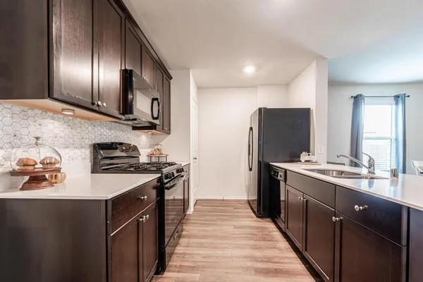 a kitchen with stainless steel appliances granite countertop refrigerator a sink a stove and wooden floor