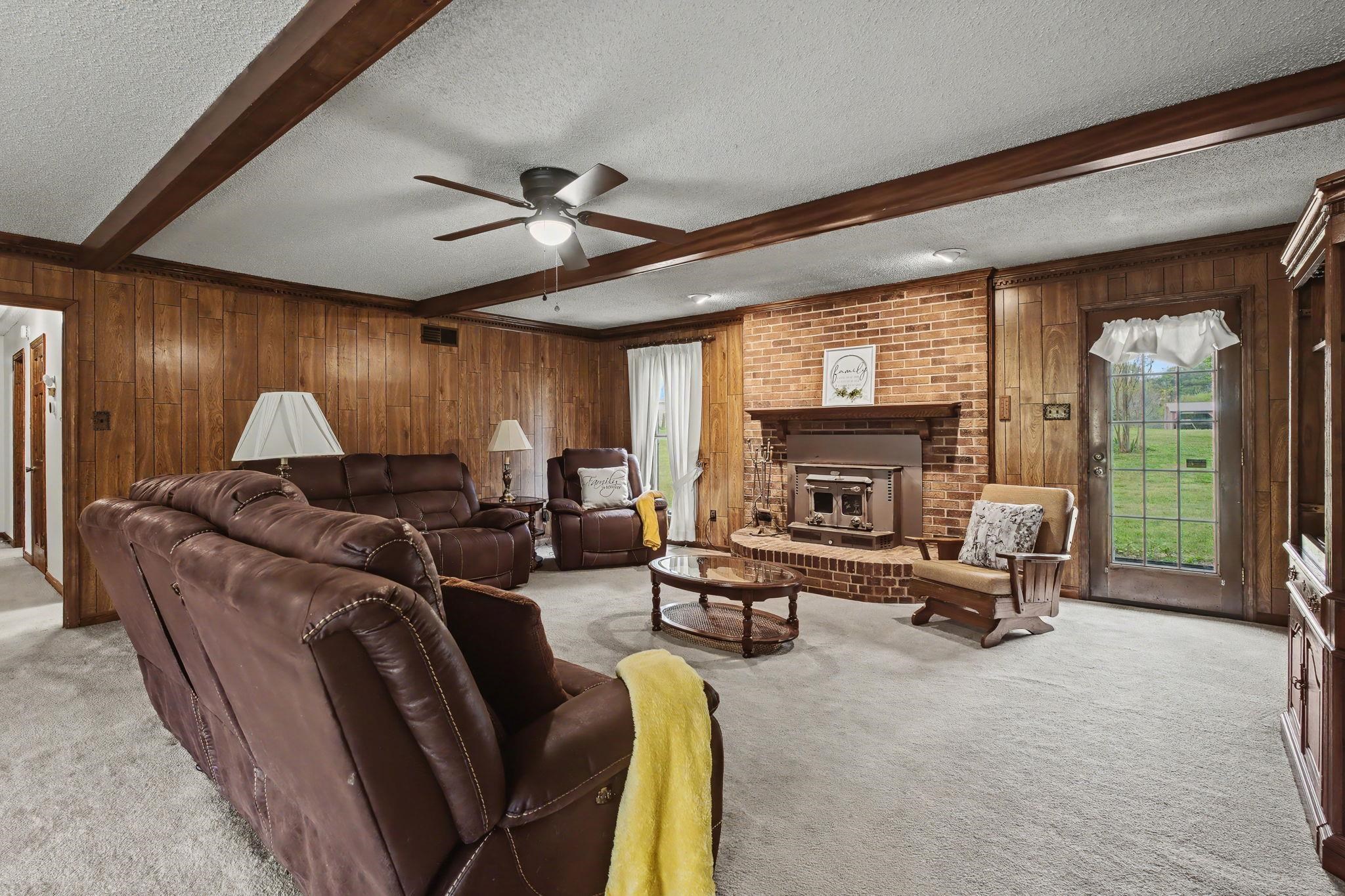 11380 Sycamore Farms Road Collierville, TN 38017 - Photo 11 of 35 Living room featuring a textured ceiling, wood walls, beamed ceiling, light carpet, and ceiling fan