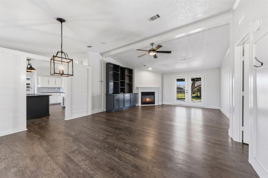 734 Northfork Road Royse City, TX 75189 - Photo 5 of 35 a view of an empty room with wooden floor and a kitchen