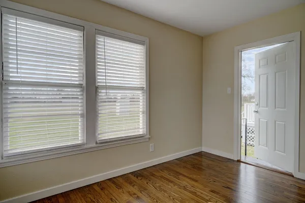 a view of an empty room with wooden floor and a window