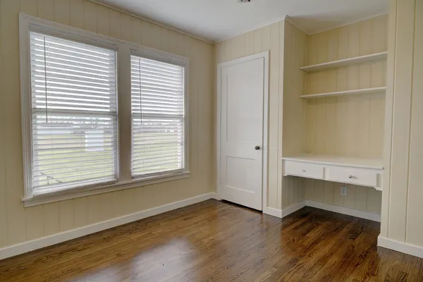 an empty room with wooden floor and windows