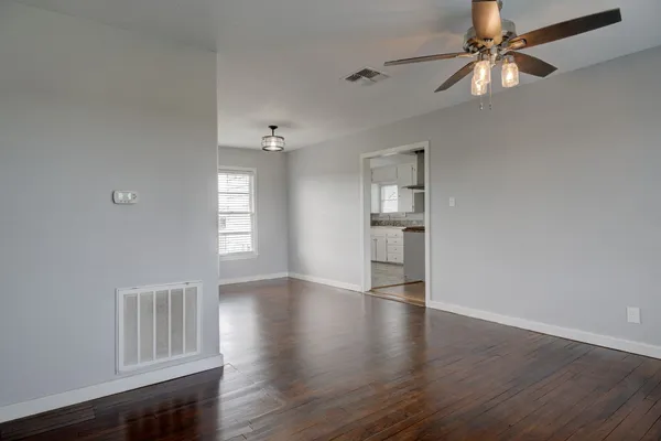 a view of an empty room with wooden floor and a window