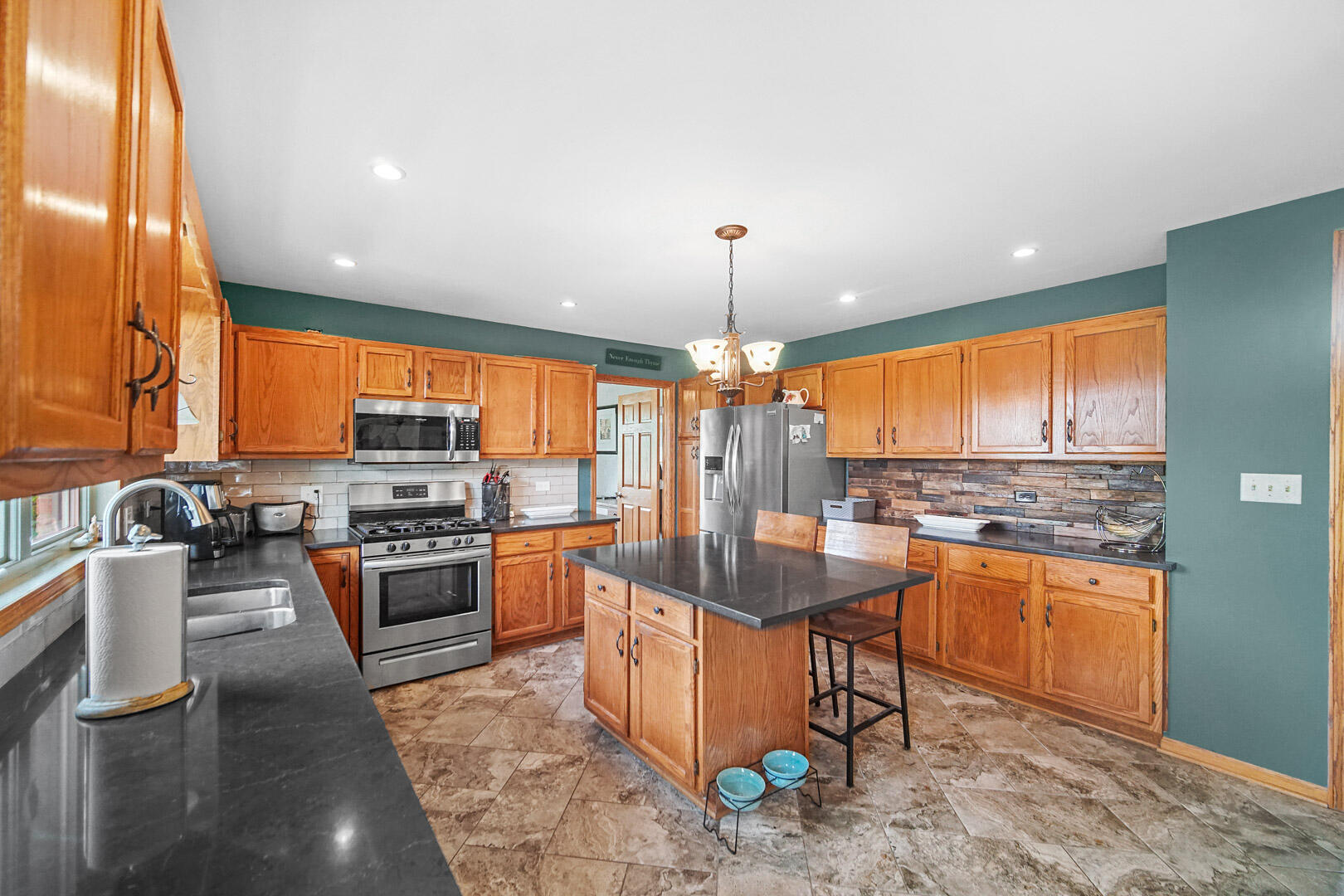 8466 Christopher Drive St. John, IN 46373 - Photo 6 of 23 a kitchen with stainless steel appliances granite countertop a stove top oven a sink dishwasher a dining table and chairs with wooden floor
