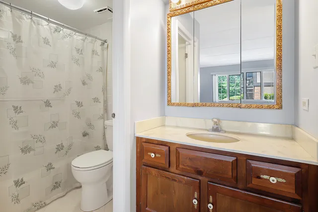 a bathroom with a granite countertop sink a toilet and a mirror