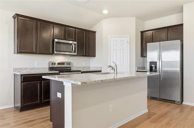 a kitchen with stainless steel appliances granite countertop a refrigerator a stove a sink and a microwave