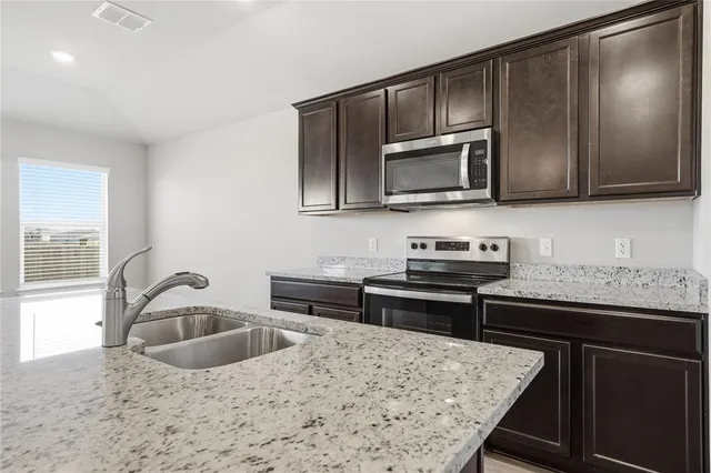 a kitchen with granite countertop a sink and steel appliances