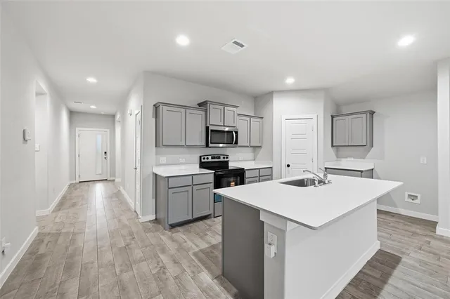 a kitchen with a sink white cabinets and stainless steel appliances