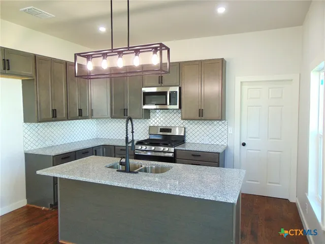 a kitchen with kitchen island stainless steel appliances a sink stove and refrigerator