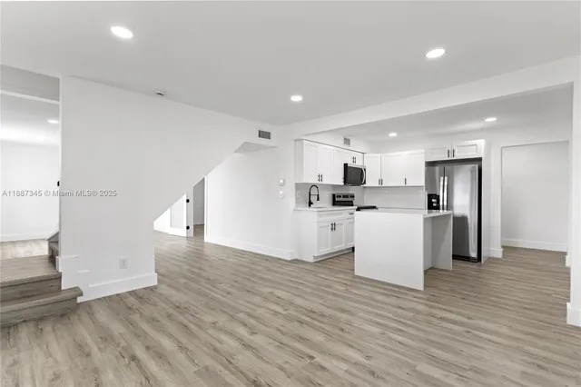 a view of a kitchen with wooden floor and electronic appliances