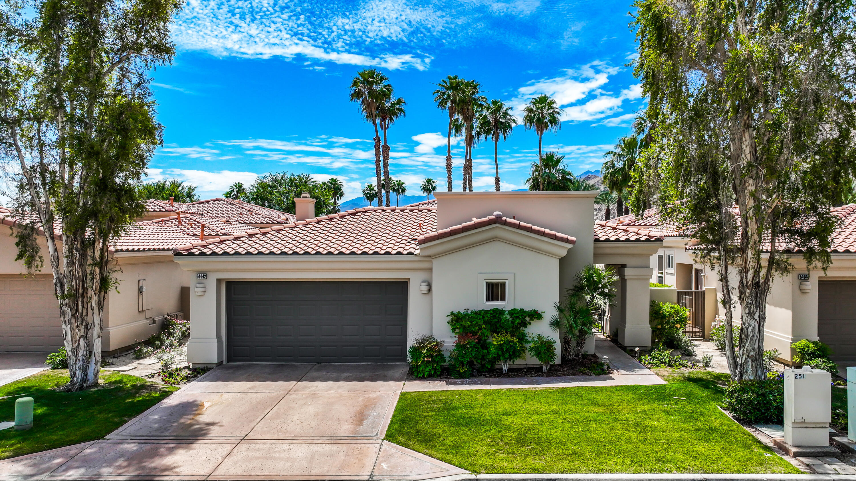 54048 Riviera La Quinta, CA 92253 - Photo 3 of 39 a front view of a house with a garden and yard