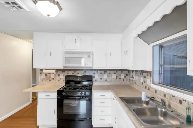 a kitchen with stainless steel appliances granite countertop a sink stove and white cabinets