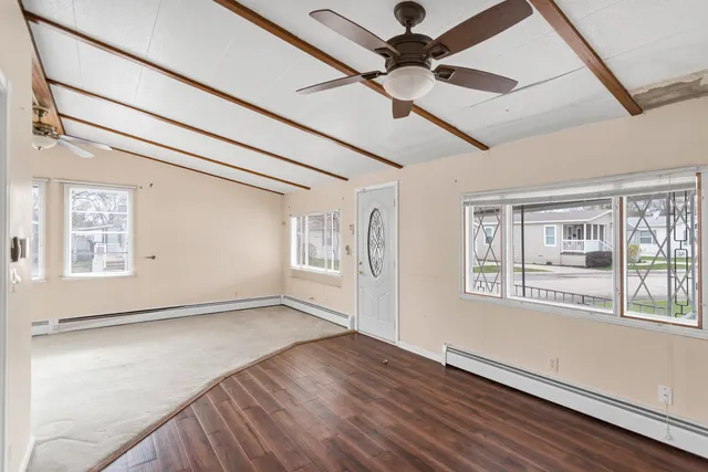an empty room with wooden floor fan and windows