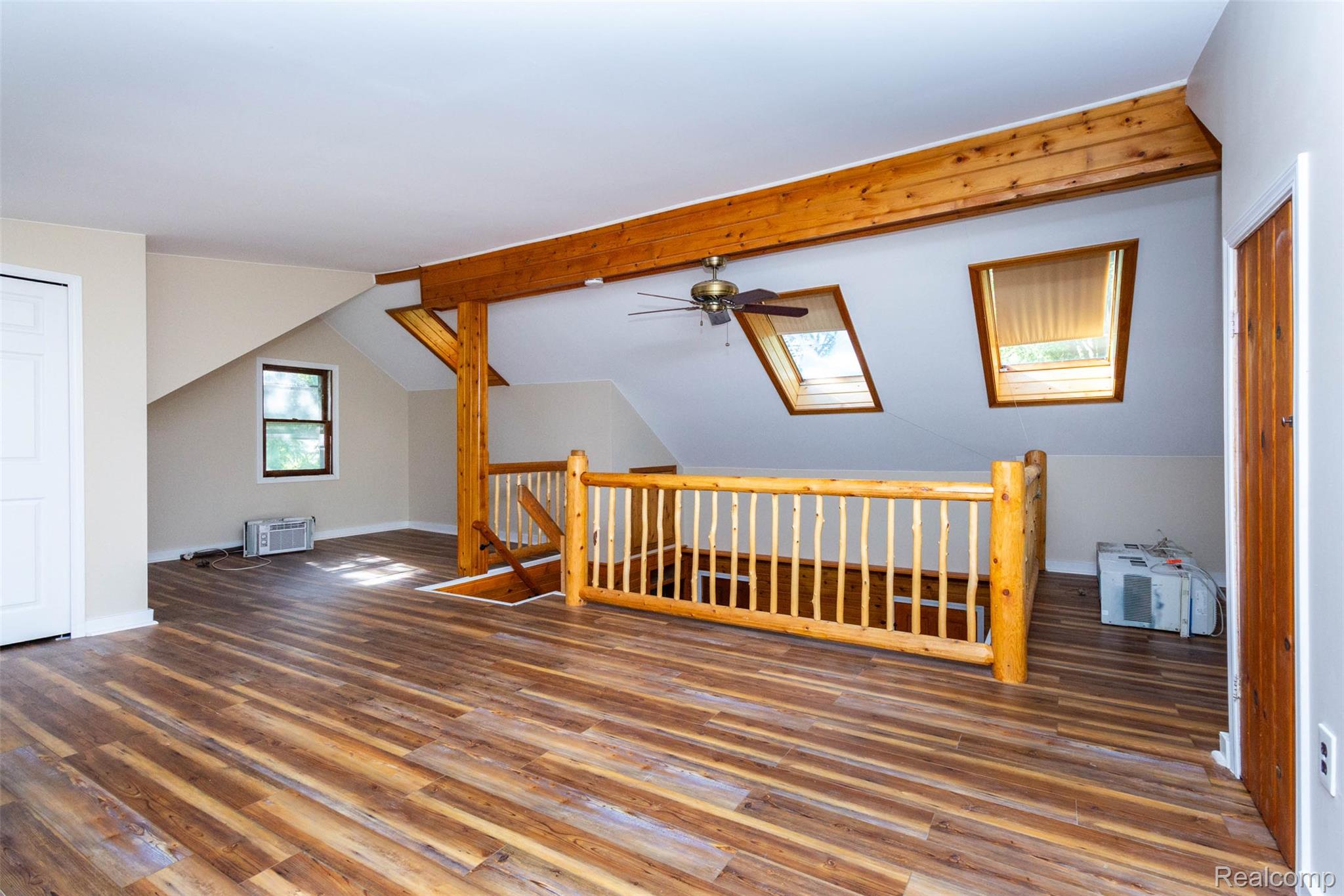 14044 Ridgemont Drive Gregory, MI 48137 - Photo 20 of 33 Loft space featuring wood-finish flooring, exposed wood beams, a wood balustrade, and two skylights