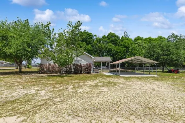 a white house with a big yard and large trees