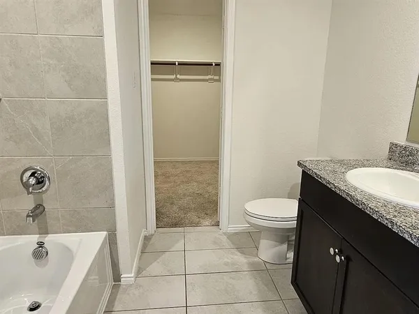 a bathroom with a granite countertop bathtub sink vanity mirror and toilet