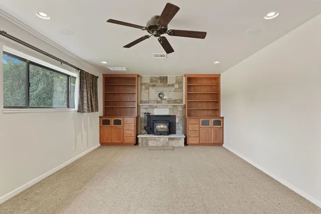 a view of a livingroom with a fireplace a ceiling fan a fireplace and windows