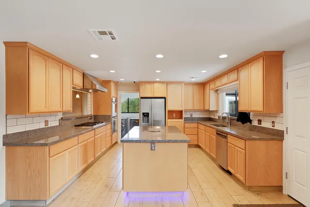 a large kitchen with kitchen island granite countertop a sink counter space and a stove top oven