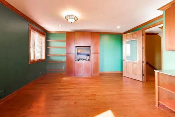 a view of an empty room with window and a kitchen
