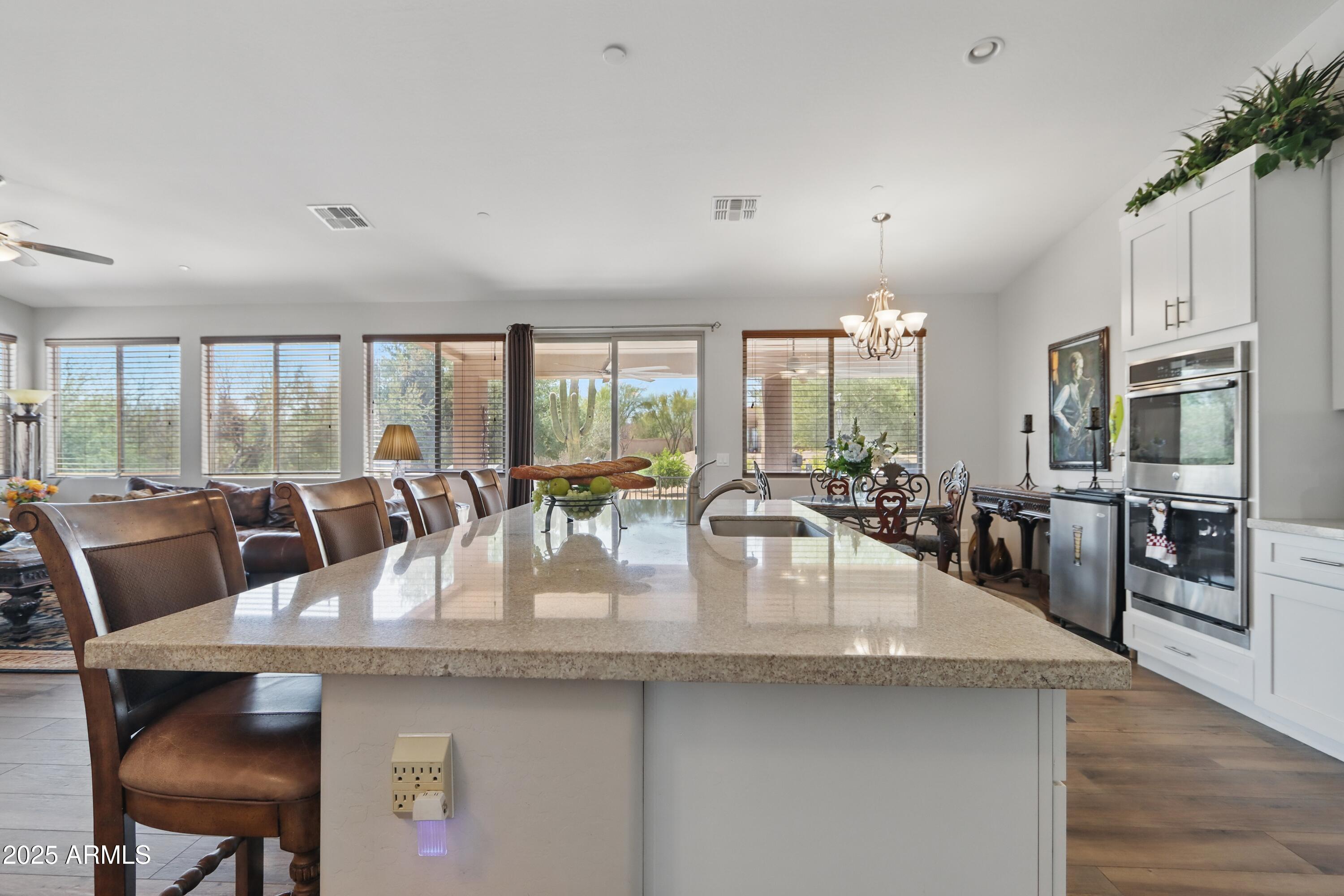 19023 East Buckskin Drive Rio Verde, AZ 85263 - Photo 14 of 58 a dining room with stainless steel appliances granite countertop a living room dining table and chairs with wooden floor