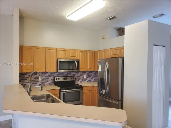 a kitchen with stainless steel appliances a refrigerator sink and microwave