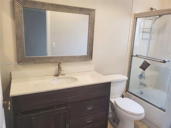 a bathroom with a sink a toilet a mirror and shower