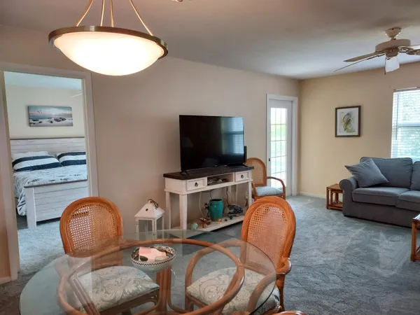 a living room with furniture a flat screen tv and kitchen view